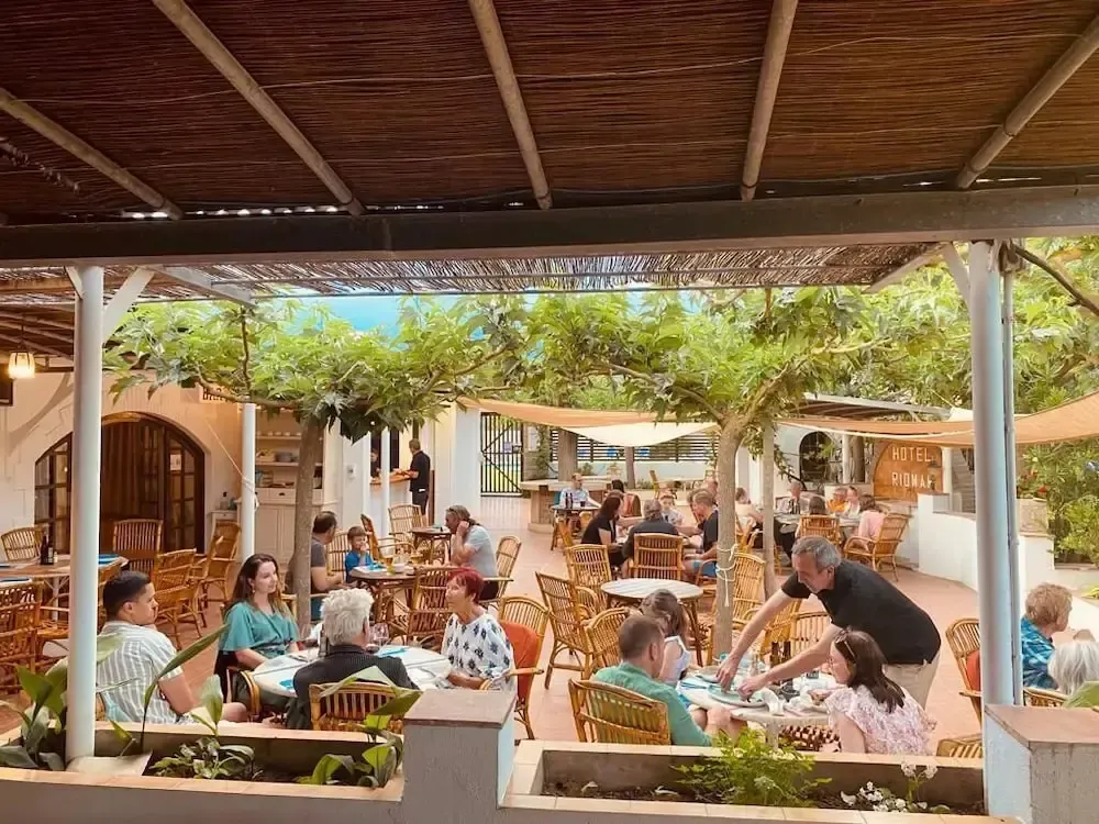 Une terrasse ombragée abrite des tables où les clients déjeunent.