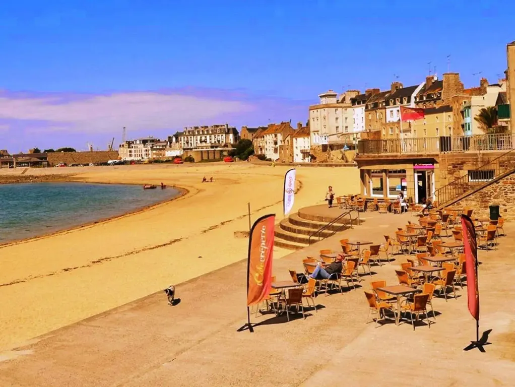 Une terrasse ensoleillée surplombe une plage de sable fin.