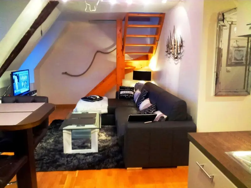 Un espace de vie intérieur avec un canapé, une table basse et un accès à une mezzanine.