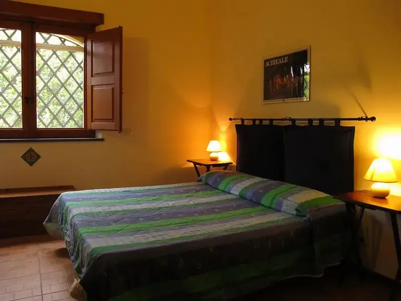 Une chambre lumineuse avec un grand lit et une fenêtre ouverte.