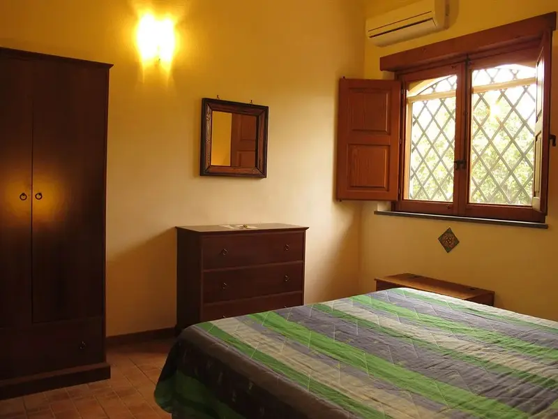 Une chambre lumineuse avec un lit recouvert d'une courtepointe colorée et un meuble en bois.
