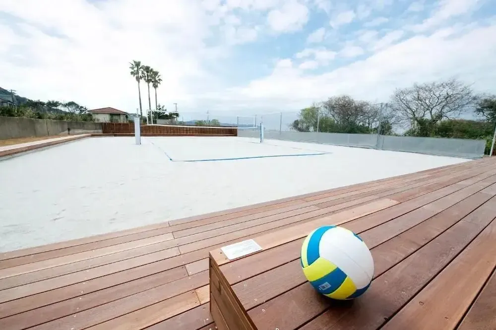Terrain de beach-volley en sable blanc avec un filet et une vue sur la mer.