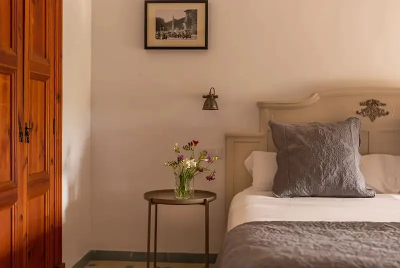 Une chambre lumineuse avec un lit et une table de chevet ornée de fleurs.
