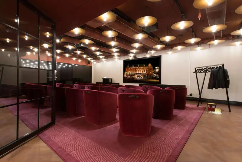 Une salle de cinéma privée avec des fauteuils rouges et un grand écran.