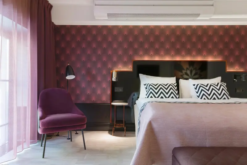 Une chambre à coucher moderne avec un fauteuil et un lit décoré de coussins.