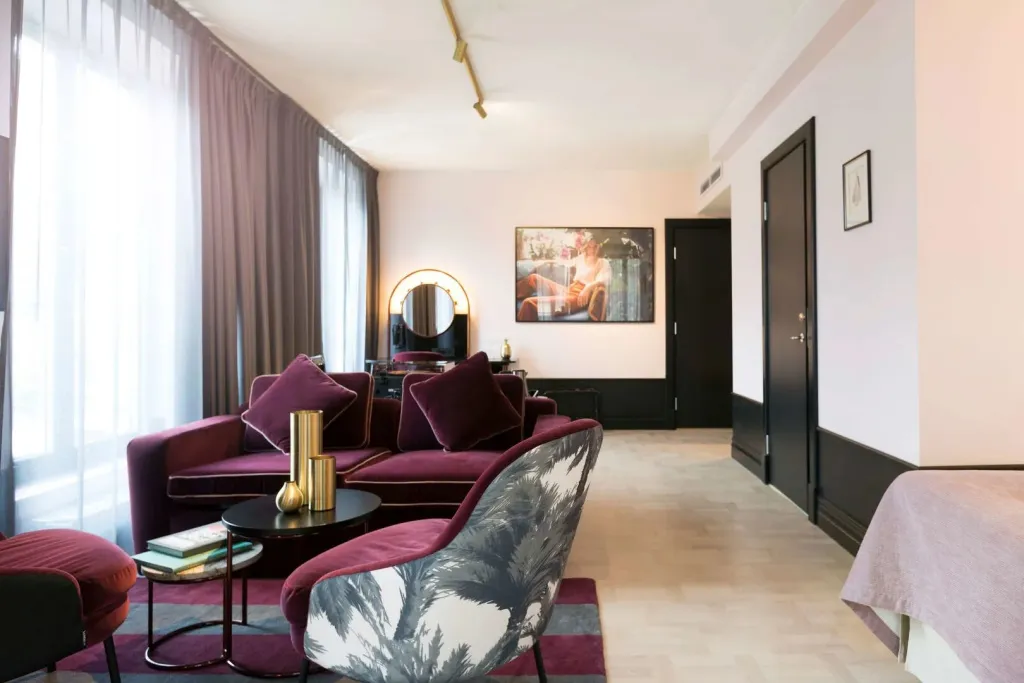Un salon moderne avec canapés violets et une coiffeuse sombre au fond.