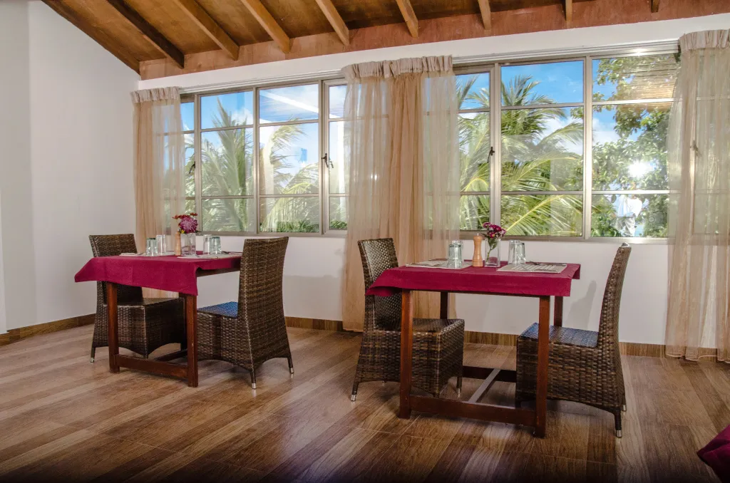 Une salle lumineuse avec des tables à manger près de grandes fenêtres.