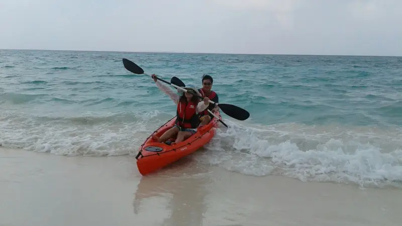 Deux personnes pagayent en kayak sur une plage ensoleillée.