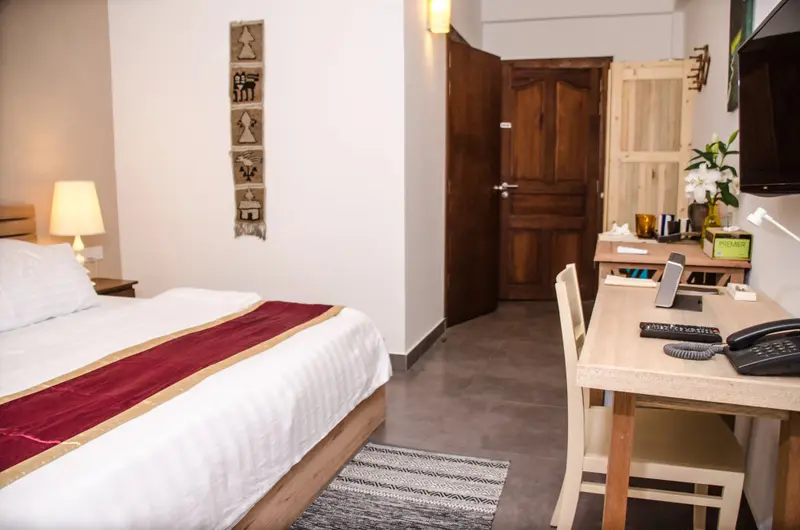 Une chambre lumineuse avec un lit recouvert d'une courtepointe et un bureau en bois.