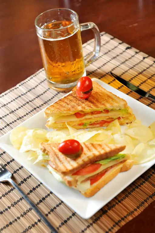 Assiette de sandwichs grillés accompagnée d'une bière et de frites.