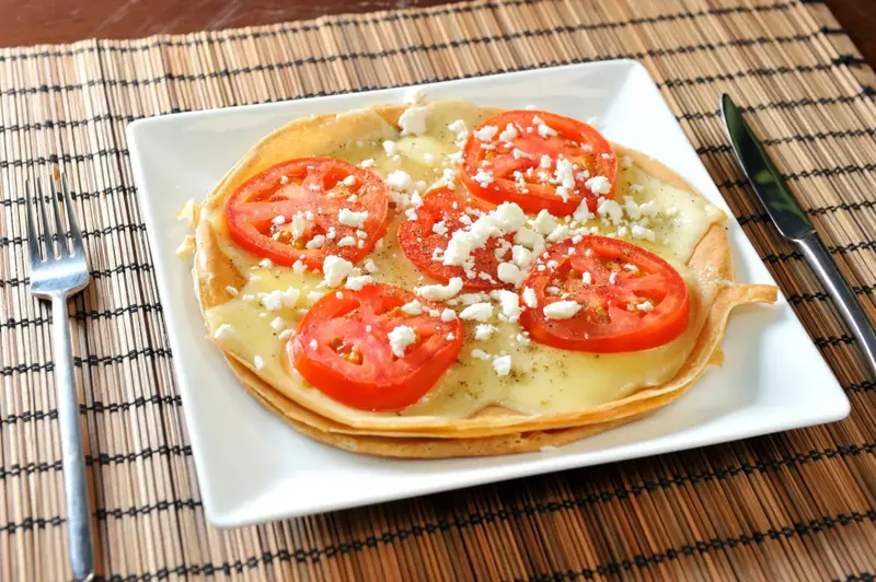 Assiette de galettes garnies de fromage, de tomates et de feta.