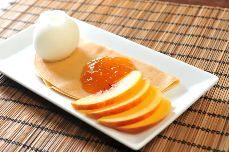 Assiette de crêpes garnies de confiture d'abricots et de fromage blanc.