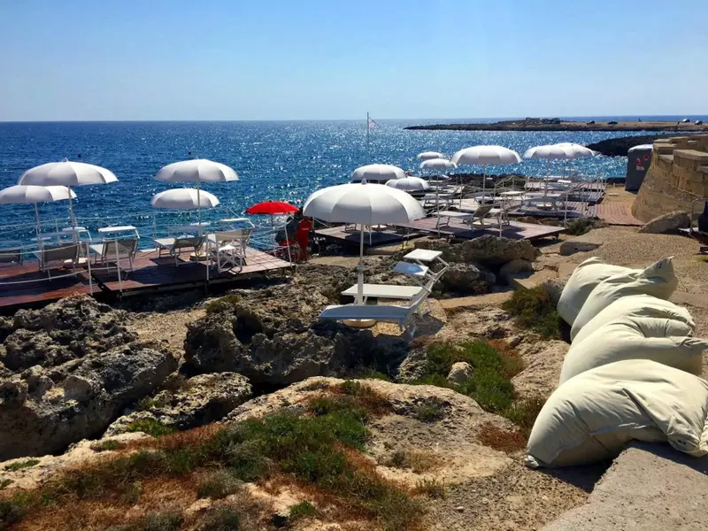 Terrasse aménagée avec des transats et des parasols au bord de la mer.