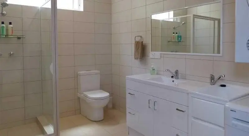 Une salle de bain claire avec douche, toilettes et lavabo.