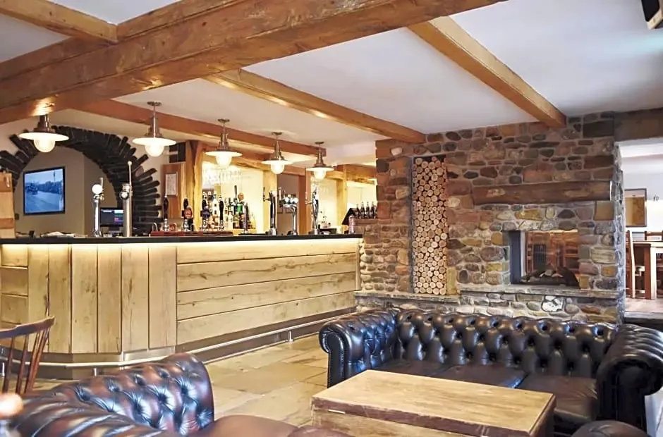 Un bar chaleureux avec un comptoir en bois et des canapés en cuir près d'une cheminée en pierre.