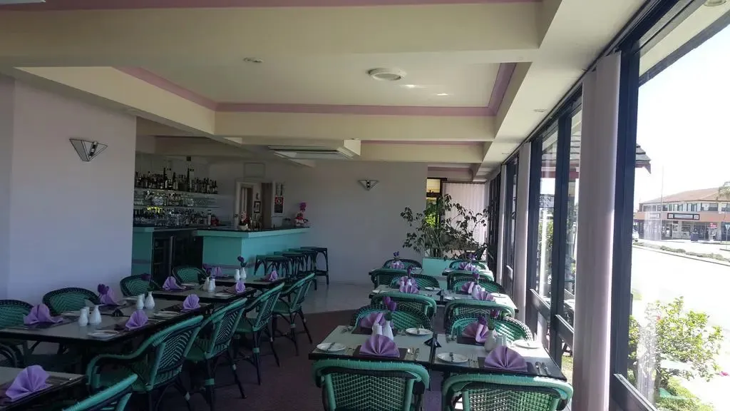 Une salle lumineuse avec des tables dressées pour le service.