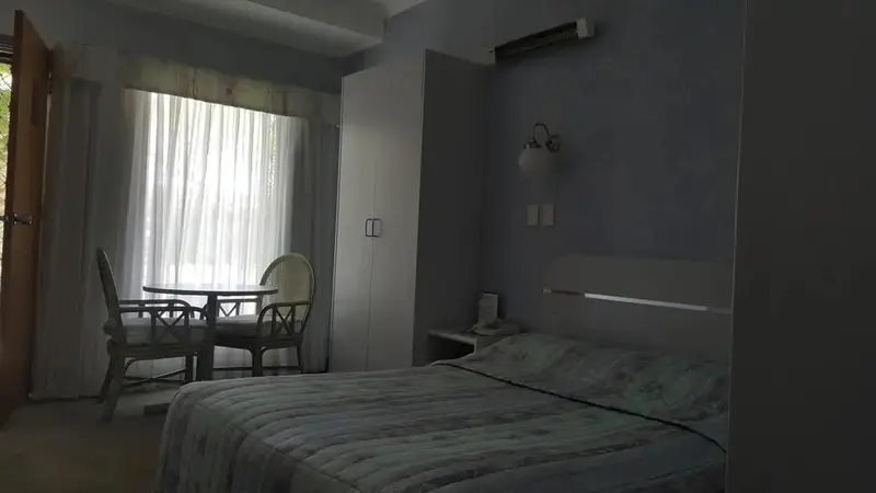 Une chambre lumineuse avec un lit et un coin repas près d'une fenêtre.