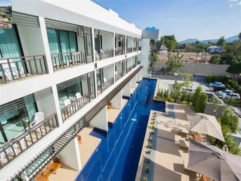 Vue aérienne d'un bâtiment blanc moderne avec une piscine rectangulaire et des transats.