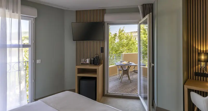 Une chambre lumineuse s'ouvre sur une terrasse avec table et chaises.