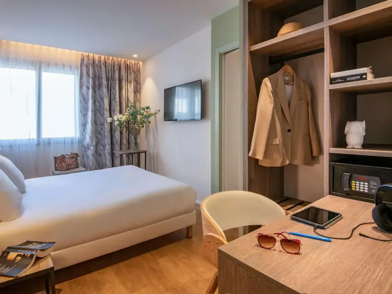 Une chambre lumineuse avec un grand lit et un espace bureau.