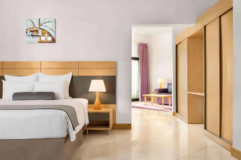 Une chambre lumineuse avec un grand lit et un espace salon attenant.