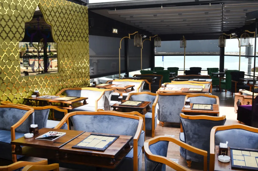 Une salle de restaurant lumineuse avec des tables dressées et une vue sur la mer.