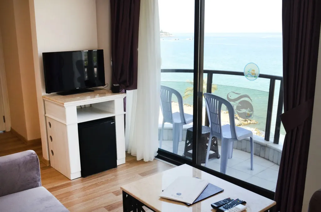 Une pièce lumineuse s'ouvre sur un balcon avec vue sur la mer.
