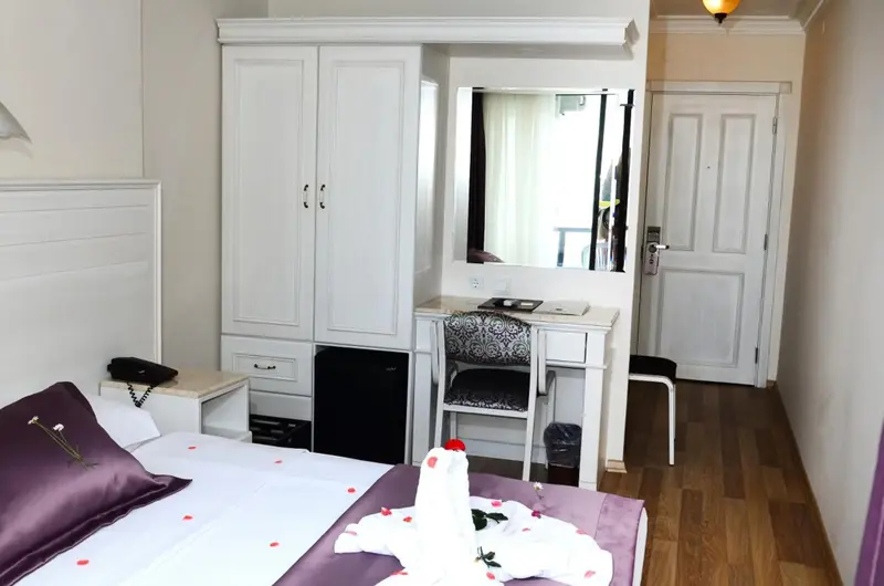 Une chambre lumineuse avec un lit décoré et un coin coiffeuse.