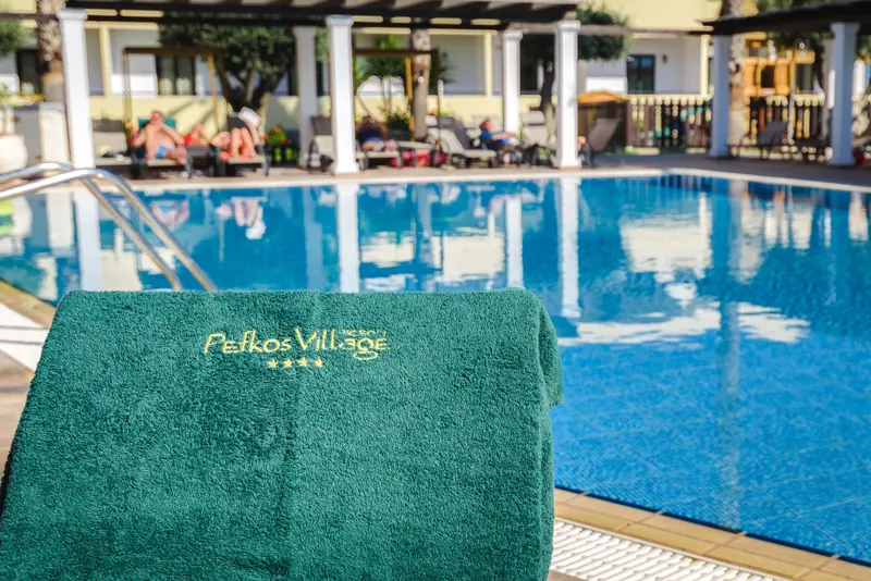 Serviette verte posée sur un transat au bord d'une piscine bleue.