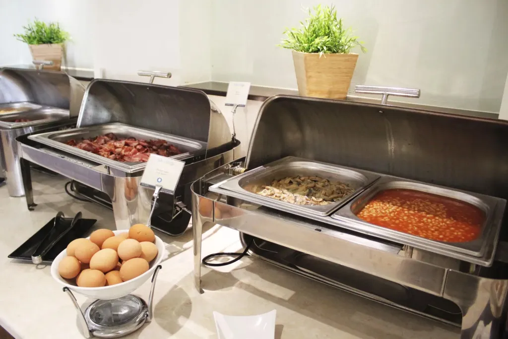 Un buffet propose des plats chauds variés et des œufs.
