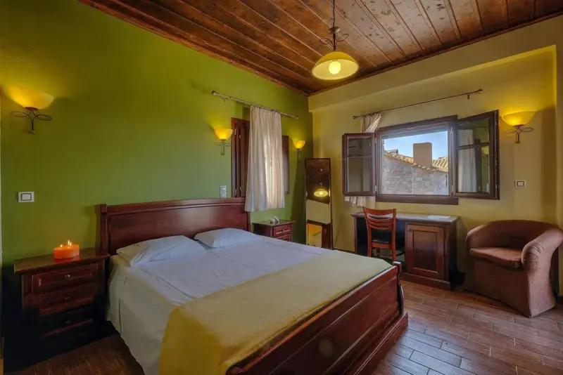 Une chambre lumineuse avec un lit double et un bureau près de la fenêtre.