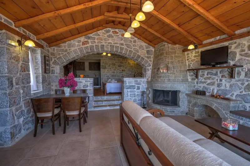 Espace de vie intérieur avec coin repas et cheminée en pierre.