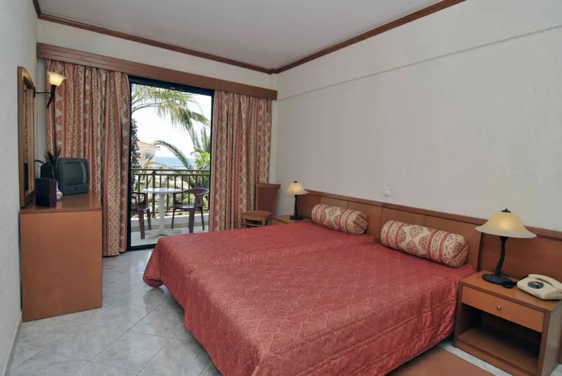 Une chambre lumineuse avec un lit recouvert d'une courtepointe et un balcon donnant sur la mer.