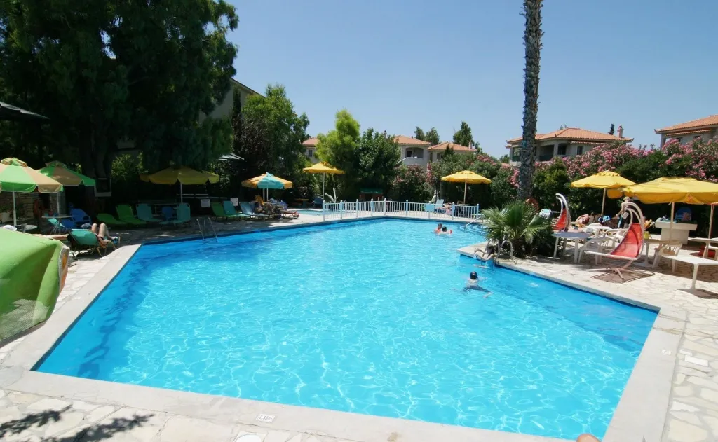 Une piscine rectangulaire entourée de transats et de parasols colorés.