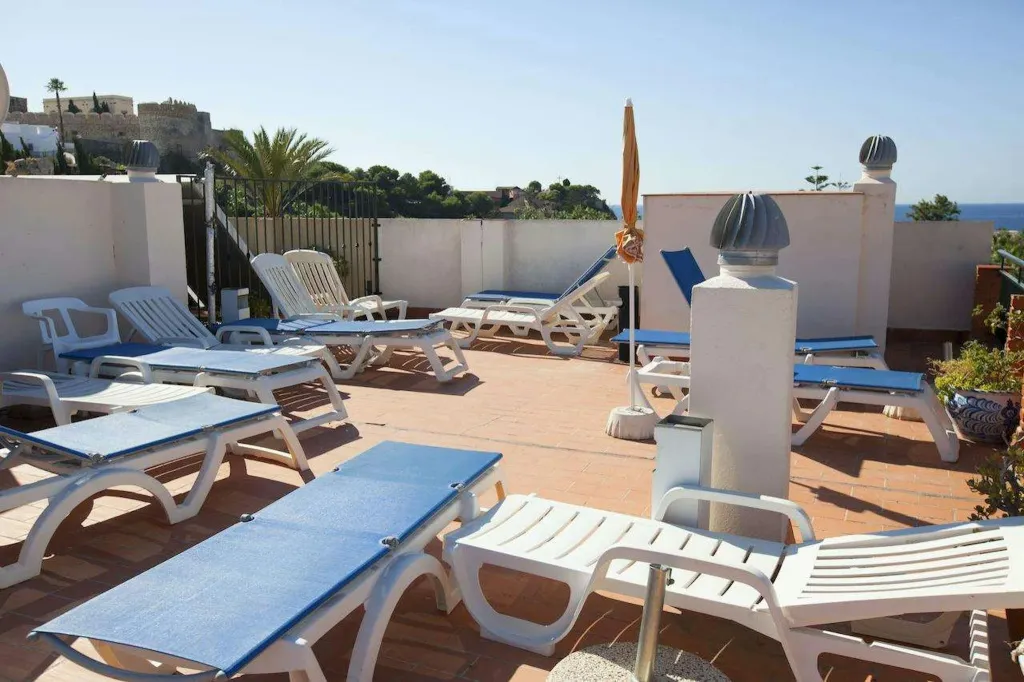 Transats bleus et blancs disposés sur une terrasse ensoleillée avec vue sur la mer.