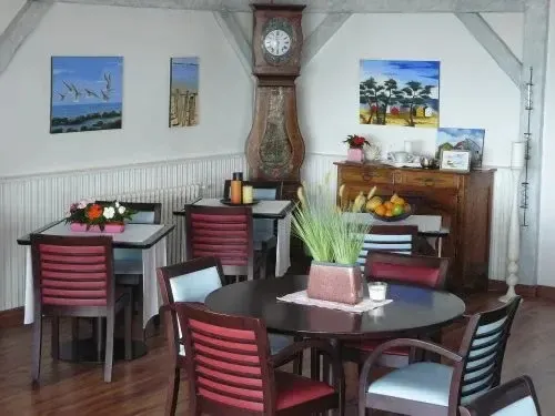 Une salle lumineuse avec des tables et des chaises disposées pour les repas.