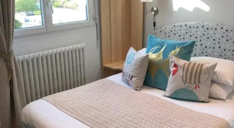 Une chambre lumineuse avec un lit décoré de coussins.