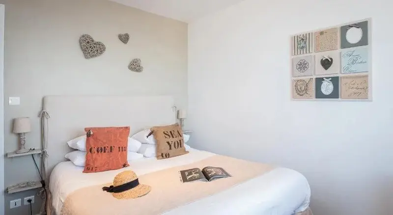Une chambre lumineuse avec un grand lit et des oreillers décoratifs.