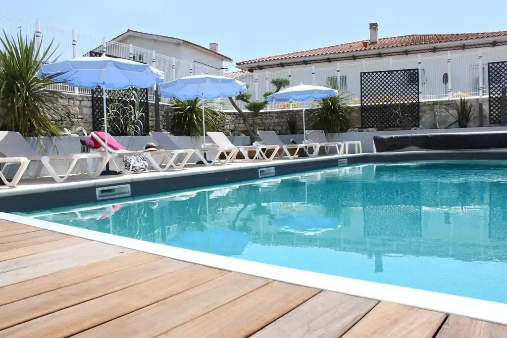 Transats bleus et blancs disposés autour d'une piscine ensoleillée.