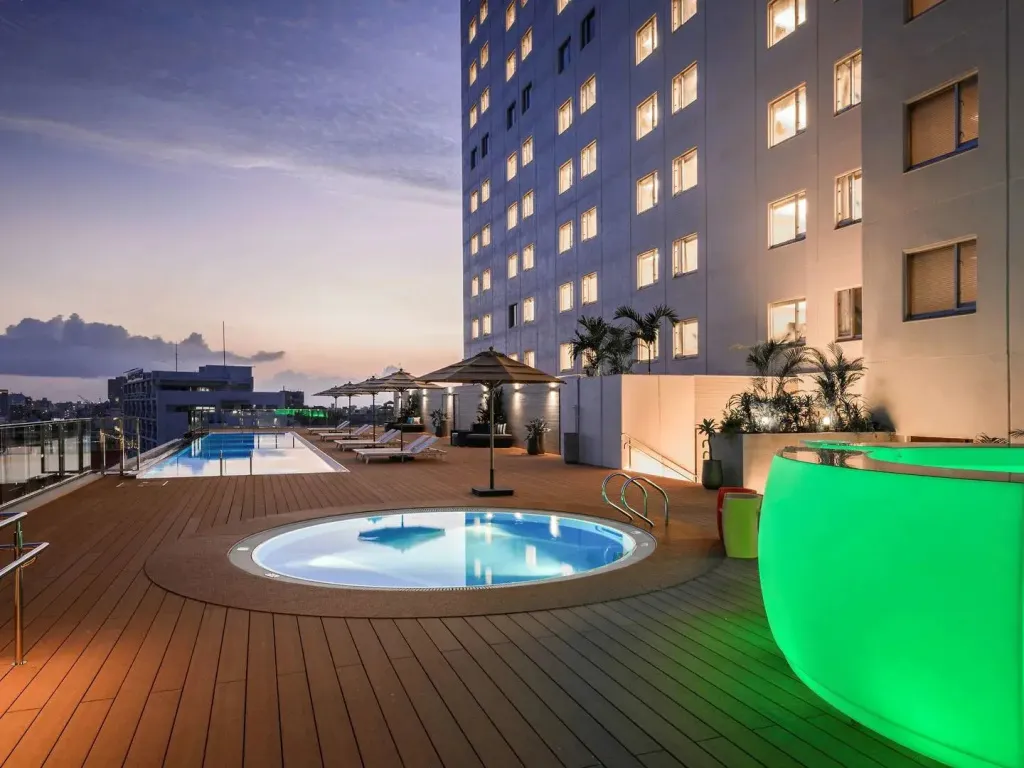Terrasse avec piscine et mobilier de détente au coucher du soleil.