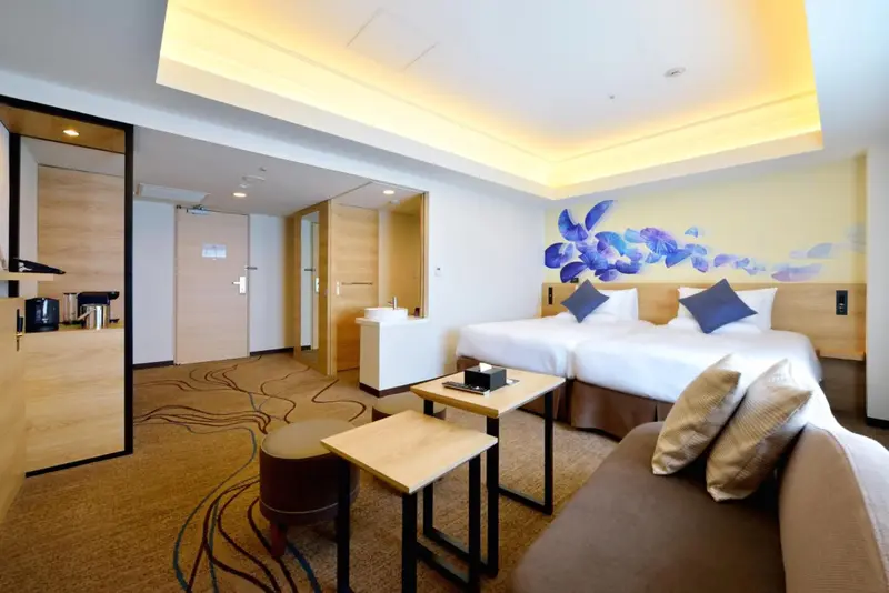 Une chambre lumineuse avec deux lits simples et un coin salon.