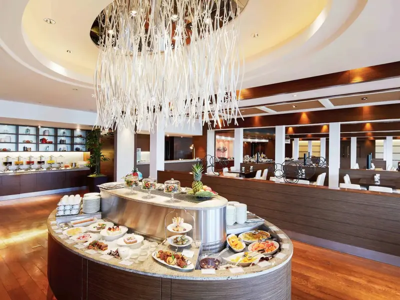 Un buffet garni de plats variés est présenté dans une salle lumineuse.
