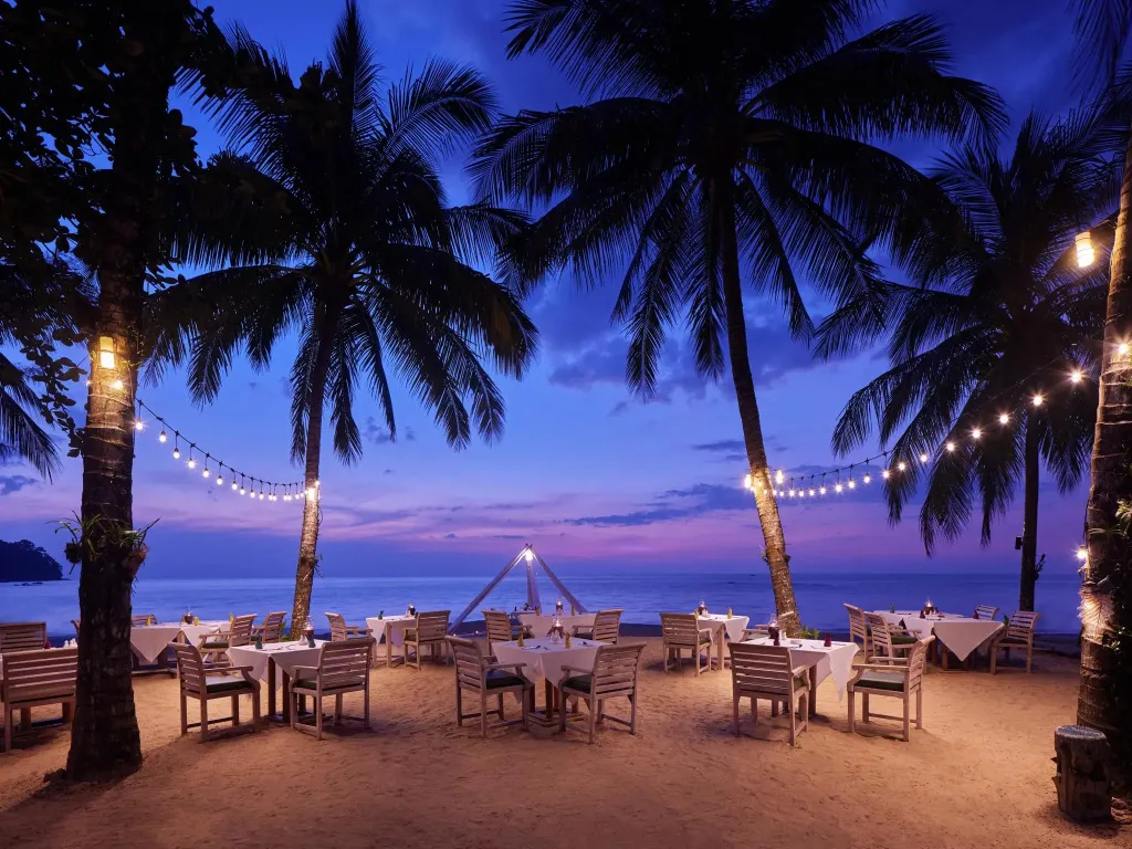 Tables dressées sur le sable au coucher du soleil.