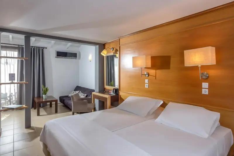 Une chambre lumineuse avec un lit double et un coin salon.