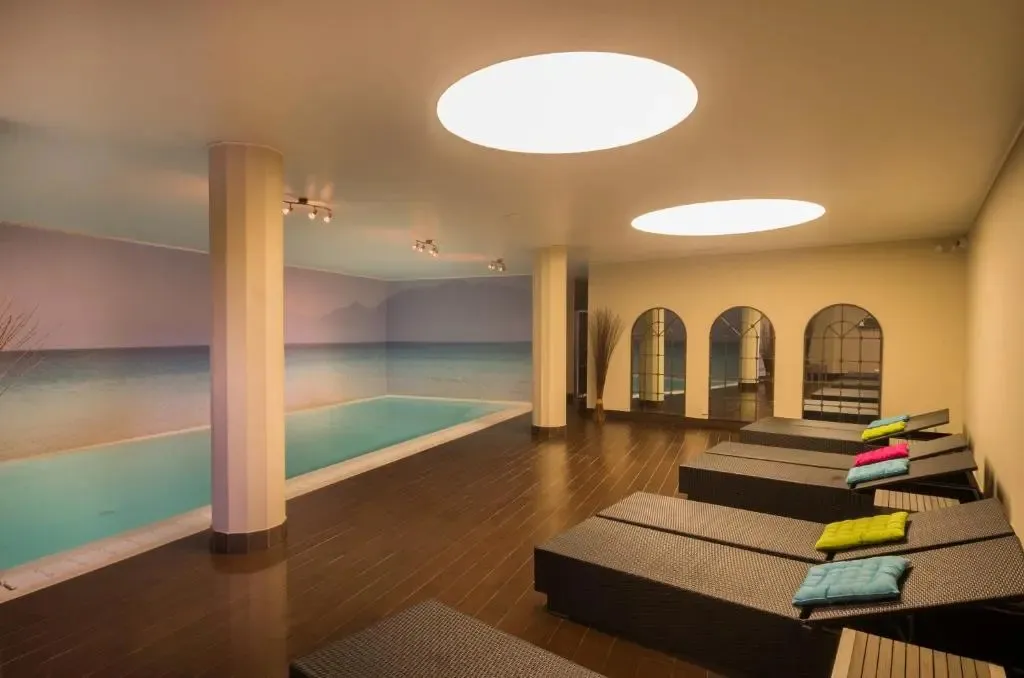 Espace de détente intérieur avec piscine et chaises longues.