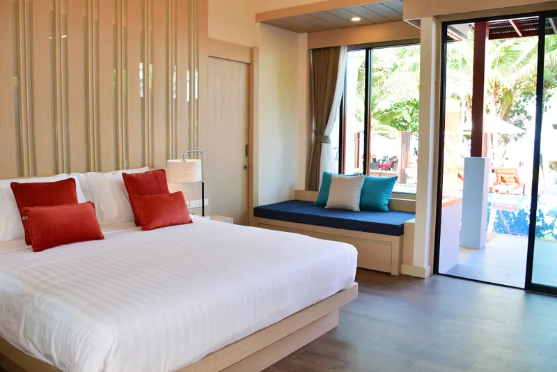Une chambre lumineuse avec un grand lit et un coin salon donnant sur une terrasse.