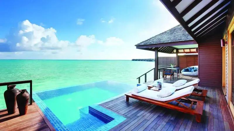 Terrasse en bois avec piscine privée donnant sur une mer turquoise.
