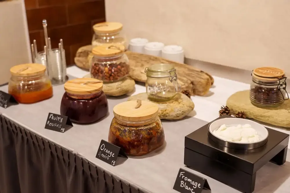 Présentation de confitures et de fromage blanc sur un buffet.
