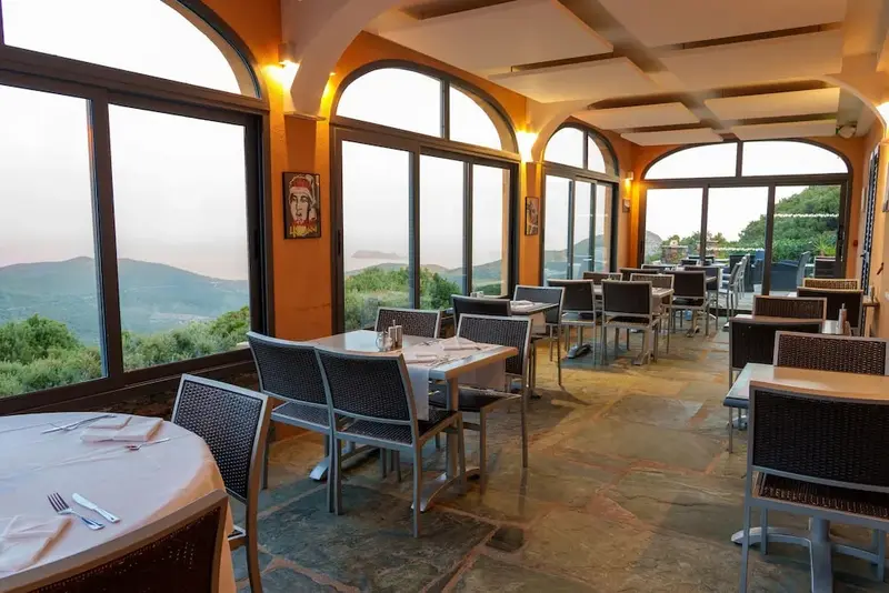 Une salle lumineuse avec des tables dressées face à un paysage montagneux.