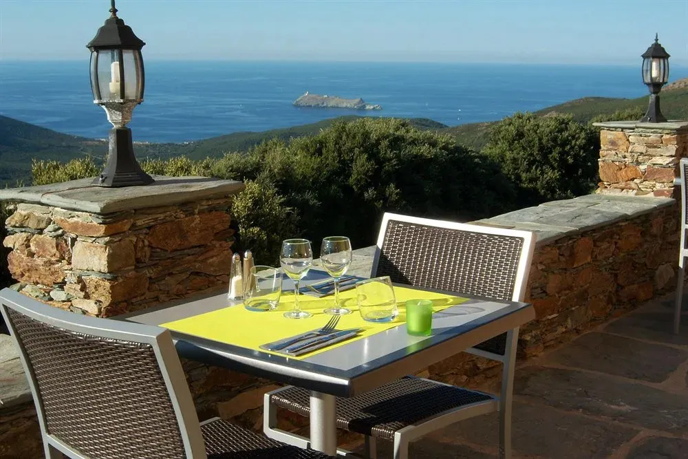 Table dressée sur une terrasse avec vue sur la mer et la côte.
